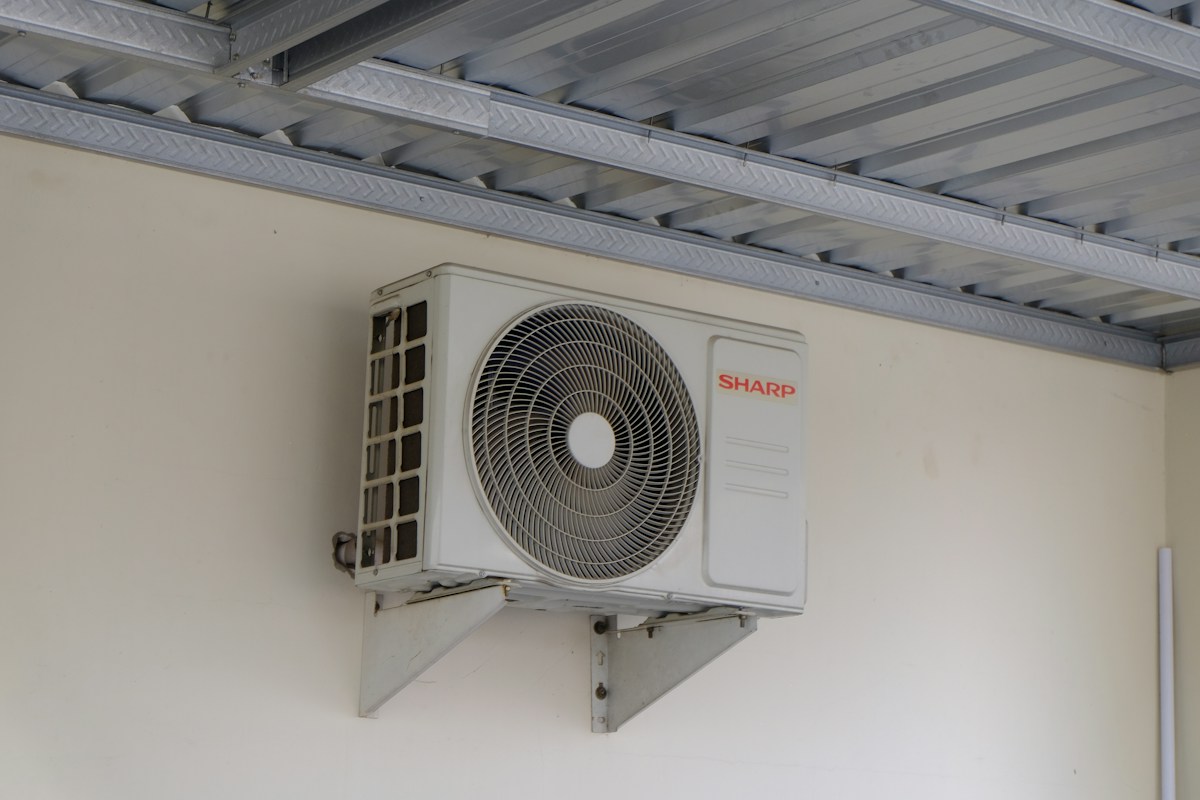 Unidade condensadora de ar-condicionado instalada em suporte na parede, sob uma cobertura