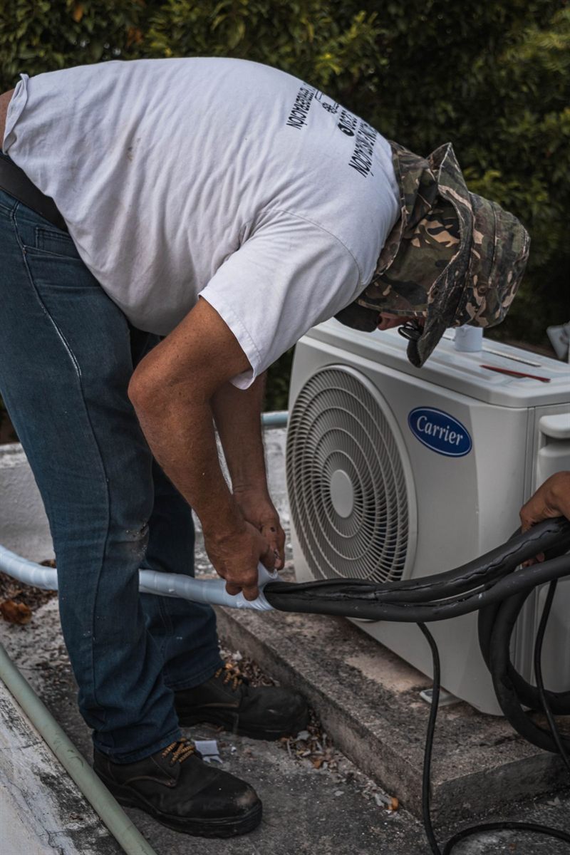 Técnico conectando a tubulação de cobre a uma unidade condensadora de ar-condicionado