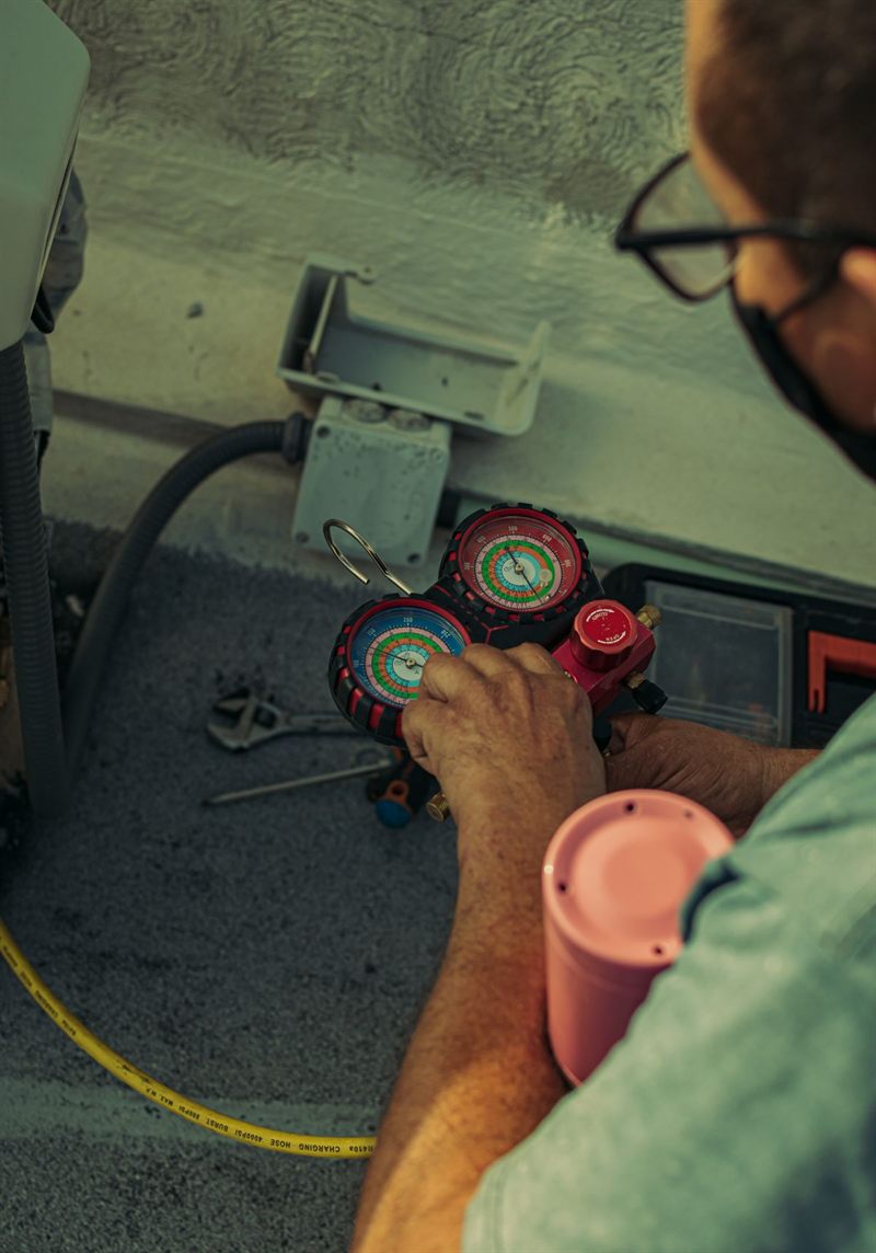 Técnico conferindo a pressão do gás refrigerante com um manifold de manômetros