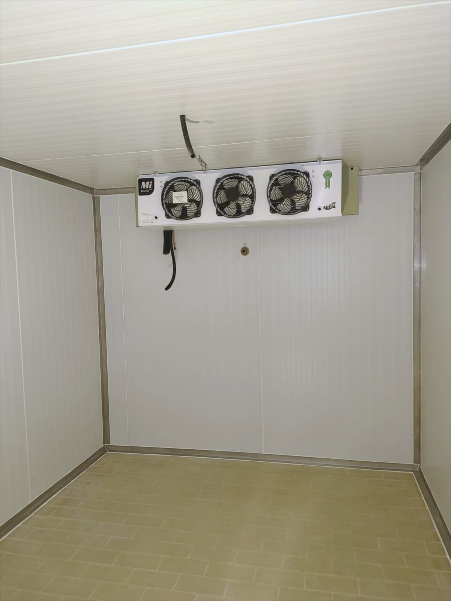 Evaporadora de três ventiladores instalada no alto da parede de uma câmara fria